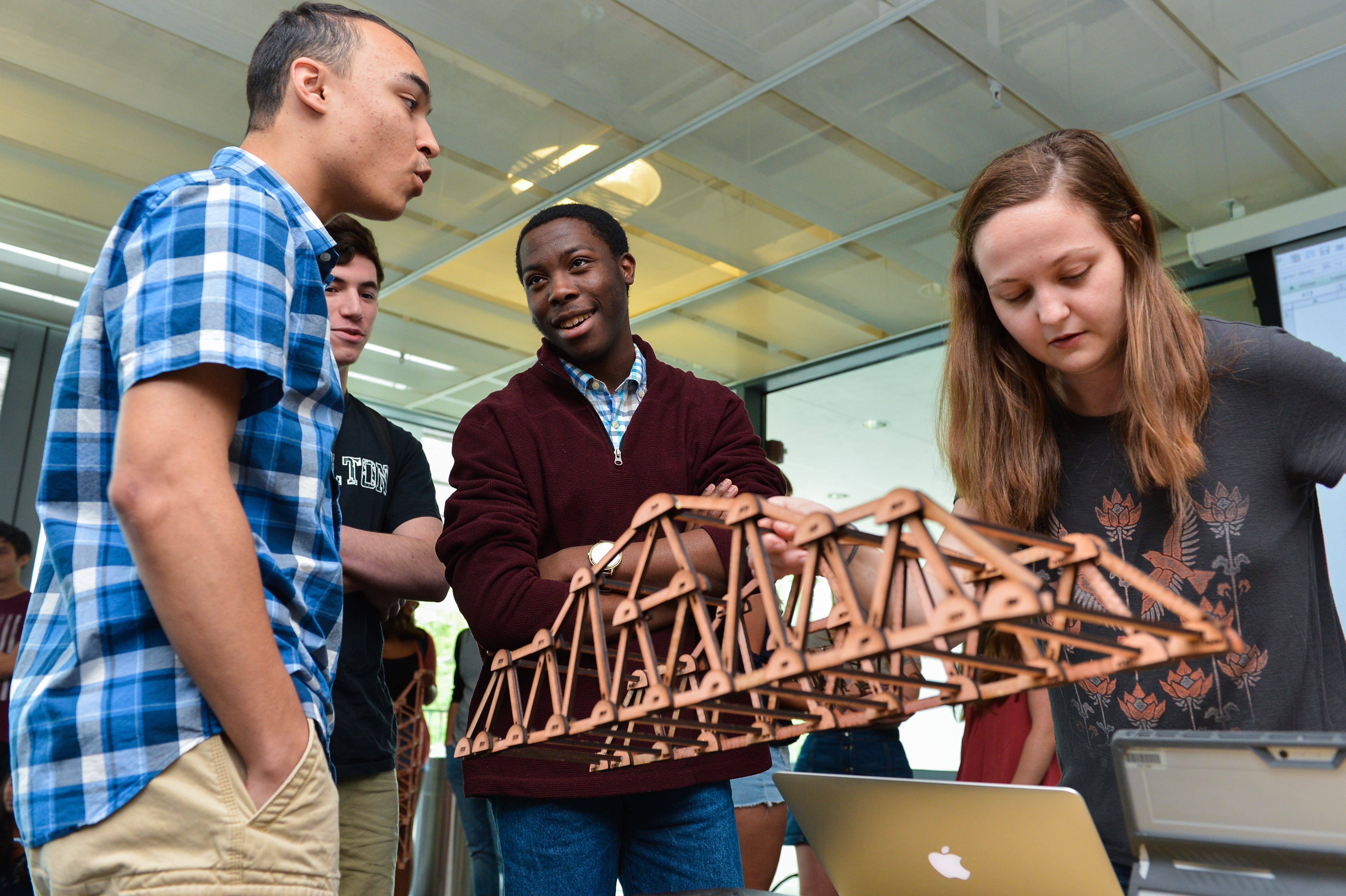 Four students testing a small wooden bridge.